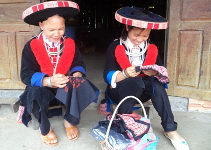 Chị Lý Thị Nhất dạy cách thêu họa tiết trang trí trên trang phục cho em gái.