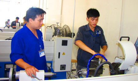 Thầy giáo đang hướng dẫn học viên tại xưởng thực hành khoa Cơ khí.