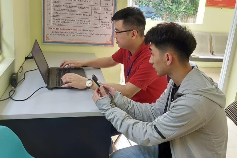 Anh Hưng (áo đỏ) hướng dẫn người dân giải quyết thủ tục hành chính. z5848059077511_07cf15091c51ed69277aa5a2f287631e.jpg